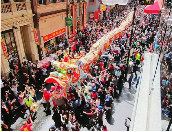 مردم در حال رقصیدن در خیابان ها در حالی که یک طرح بزرگ از یک اژدها را در طول سال نو چینی حمل می کنند.